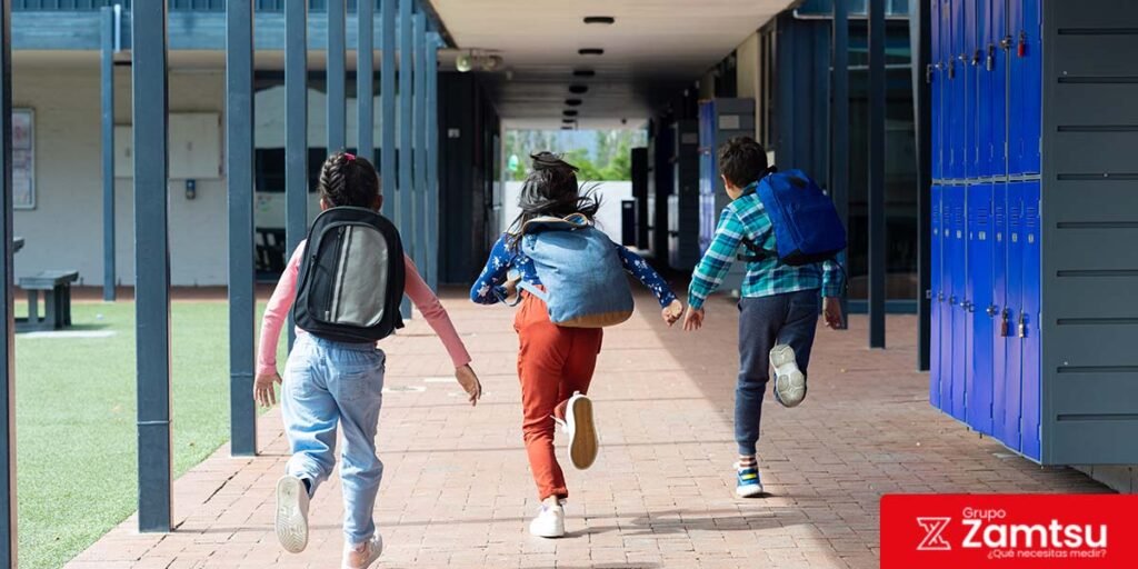 Niños corriendo en un colegio, entorno donde las normas de ruido ayudan a controlar niveles acústicos y proteger la salud auditiva.